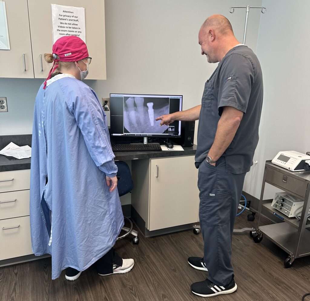 oral surgeon and assistant looking at x-ray of dental implant