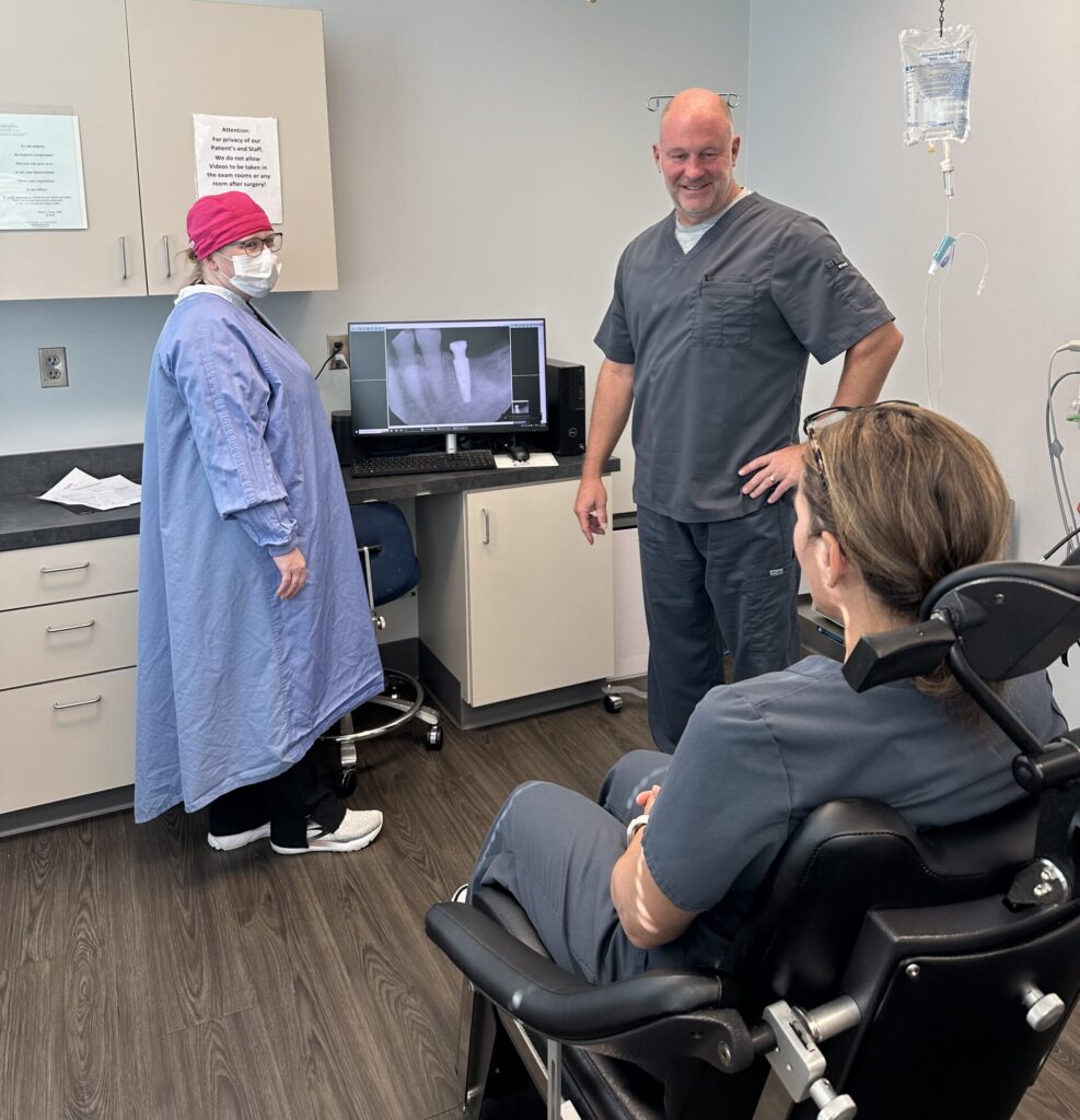 oral surgeon and assistant smiling at a person sitting in the dental chair