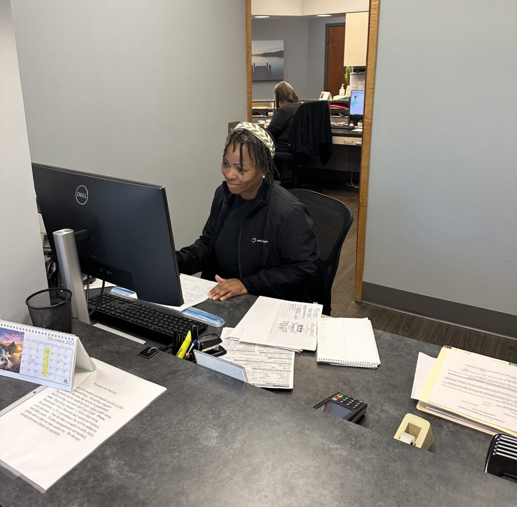 Carolina OMS employee sitting at a computer smiling